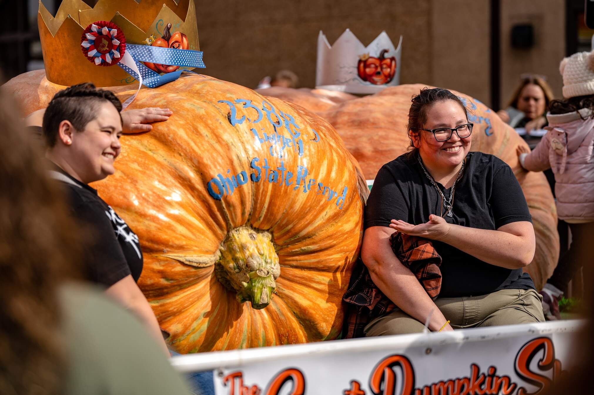 Visitors smiling with a giant prize-winning pumpkin at the Circleville Pumpkin Show