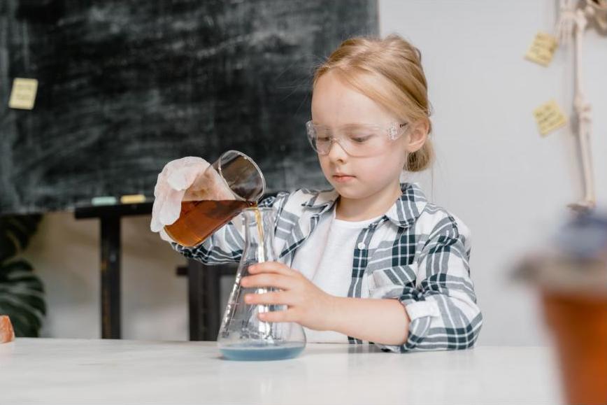 Child in safety goggles doing a hands-on STEM science experiment, generic stock photo
